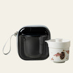 Guppy-pattern porcelain travel tea set and black zip case on a warm cream background