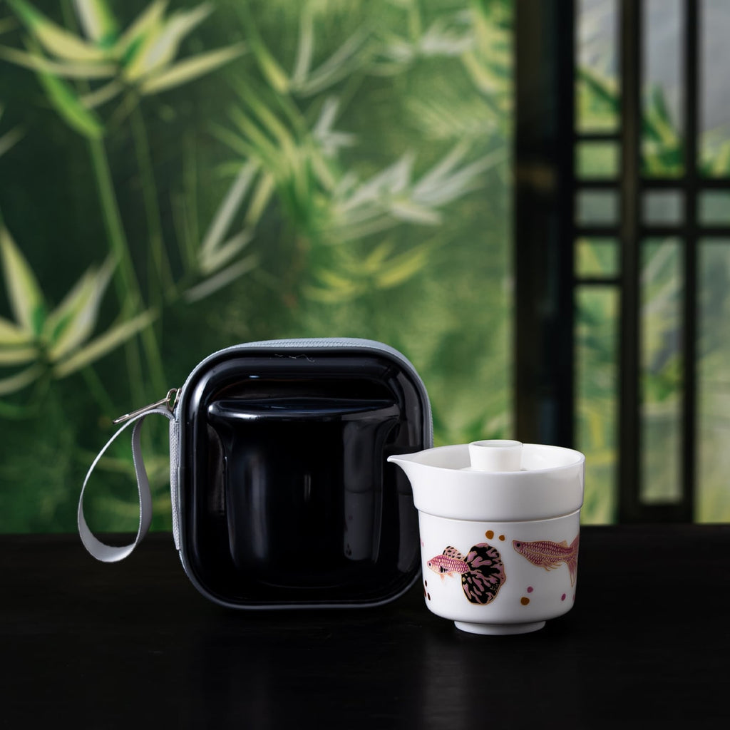 Guppy-pattern porcelain brewer and cup with black zip case before a green bamboo backdrop
