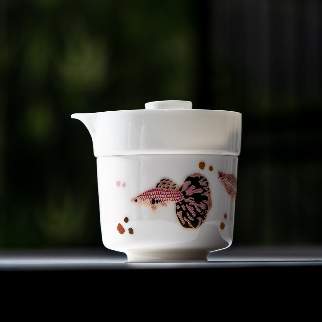 Close view of lidded white porcelain brewer nested over a pink-and-black guppy cup