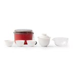 Red round travel case with a white gaiwan, tasting cup and clear pitcher on a bright background