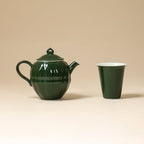 Dark green round teapot beside a matching tapered cup on a beige background
