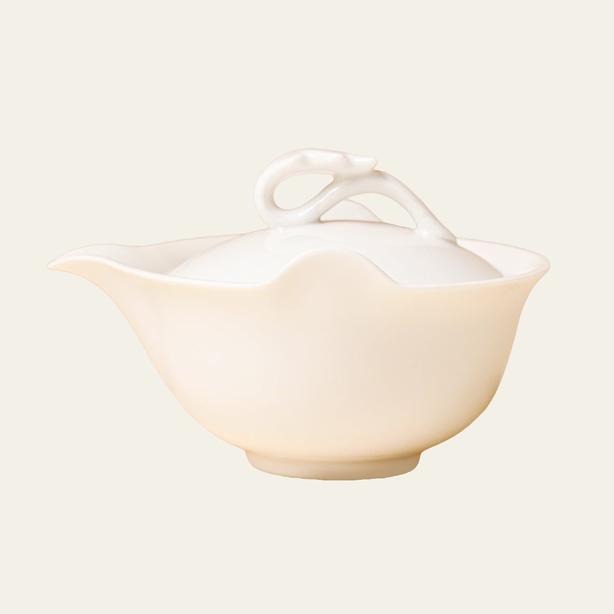Ivory-white teapot shown straight on against a pale cream background with its spout facing left