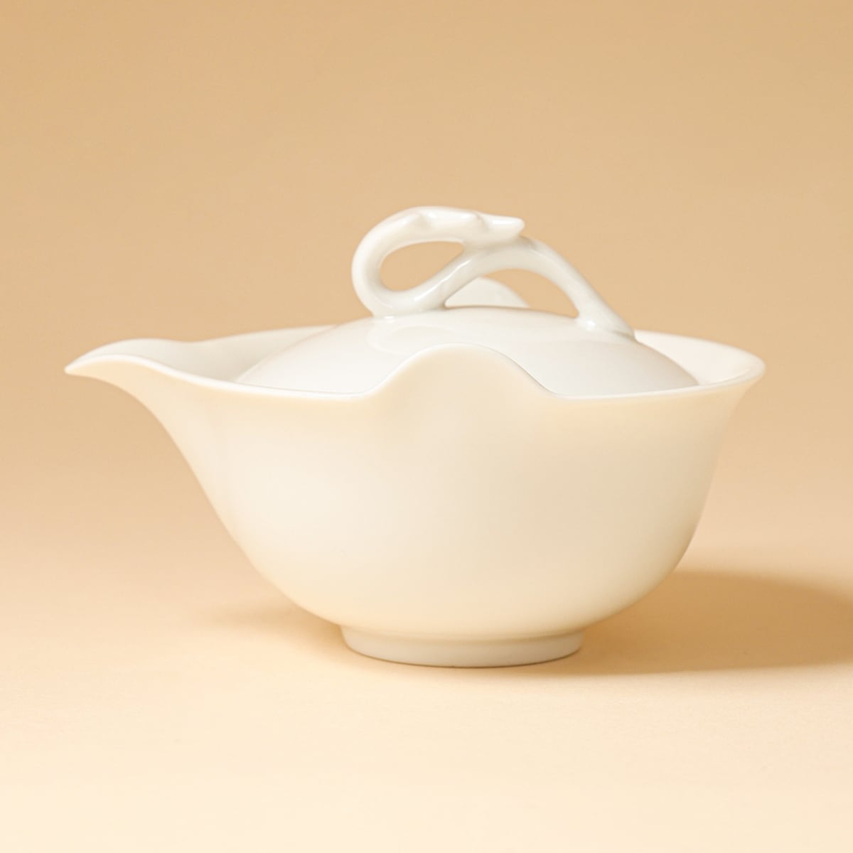 Three-quarter studio view of the ivory-white teapot on a warm beige background