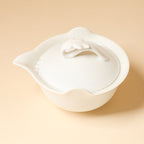 Top view of the ivory-white teapot showing the loop lid handle, pouring spout and interior filter holes