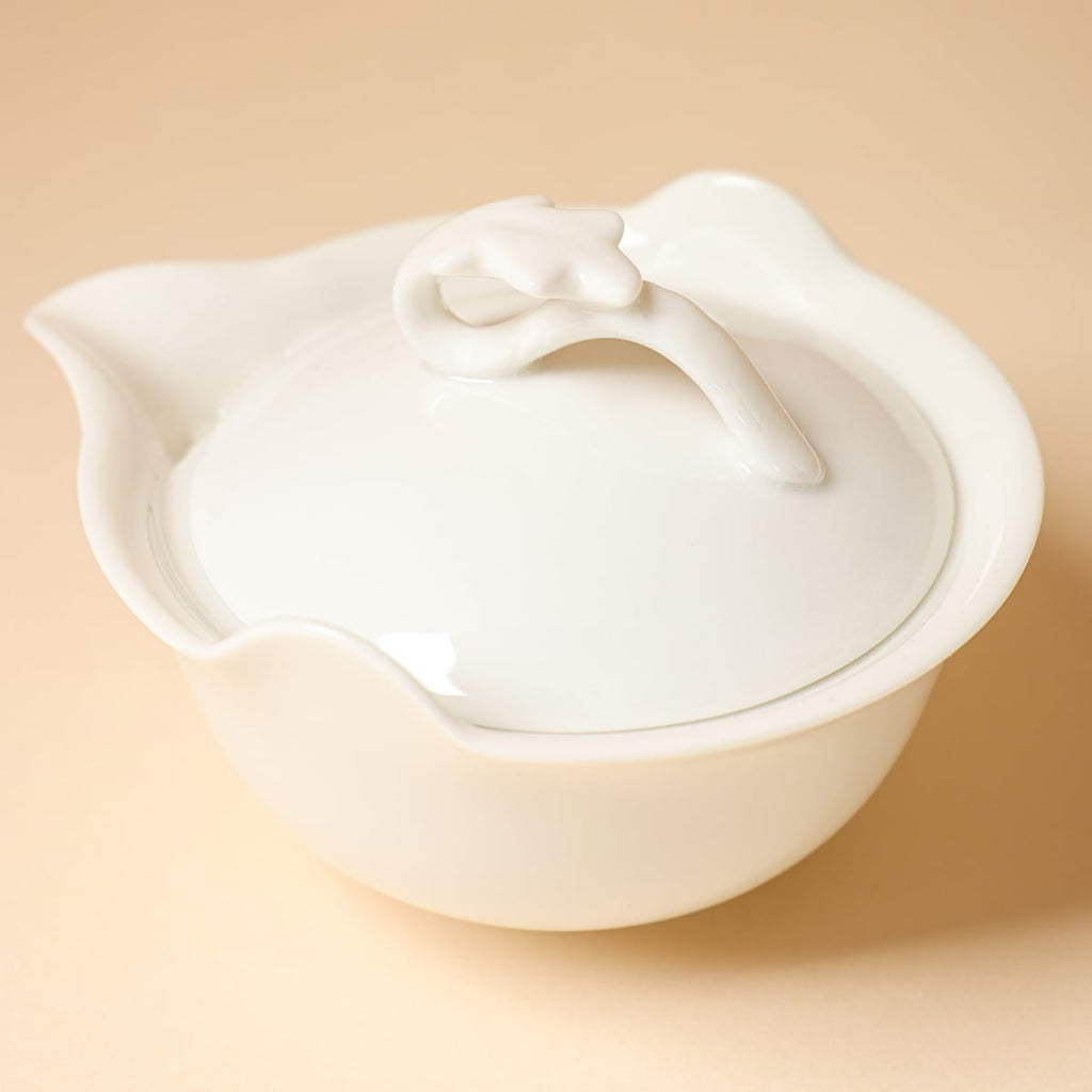 Close angled view of the teapot lid, sculpted loop handle, flared rim and pouring spout