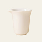 Ivory-white handleless pitcher shown straight on against a pale cream background