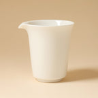 Studio view of the tall ivory-white pitcher with its pouring lip facing left