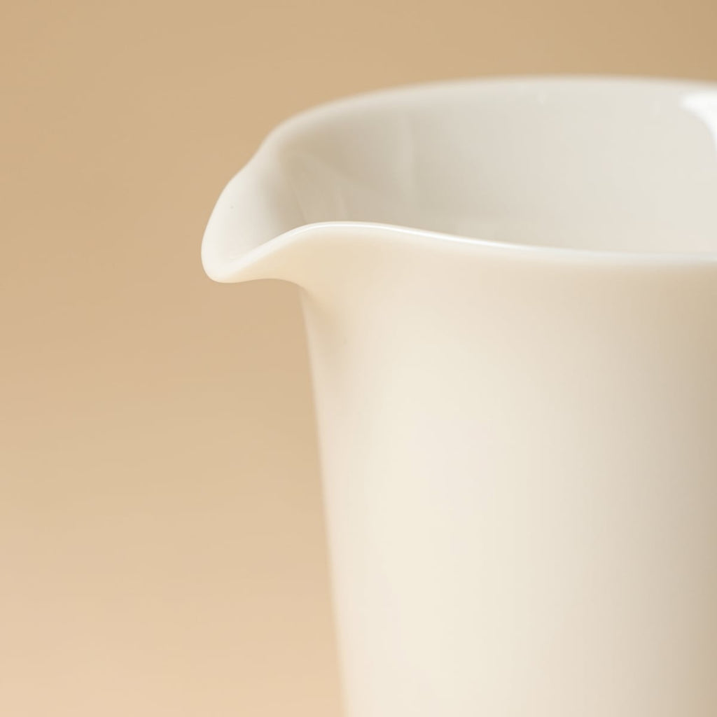Close-up of the ivory-white pitcher's curved rim and pouring lip