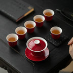 Six red-and-white tasting cups arranged around a matching lidded gaiwan
