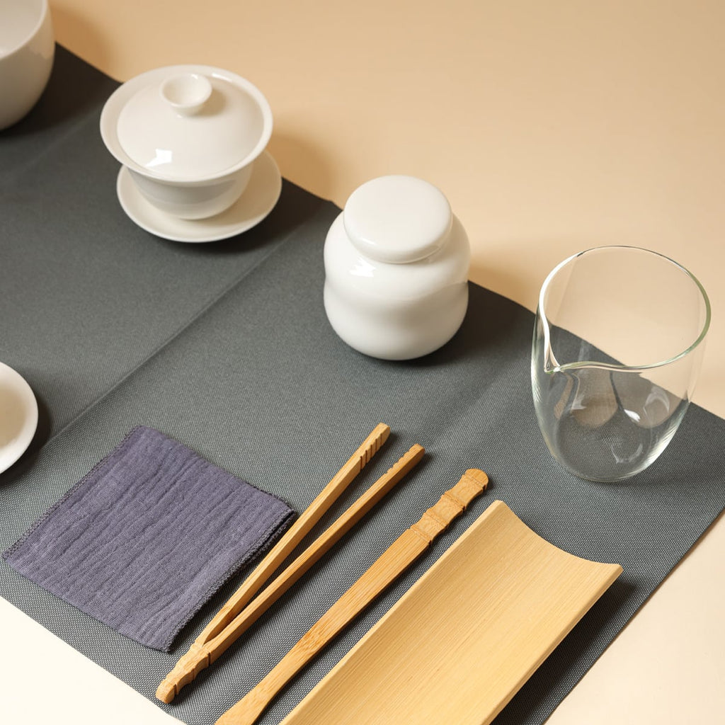 Close view of clear fairness pitcher, tea caddy, gaiwan, tea tools, tea towel and dark tea mat