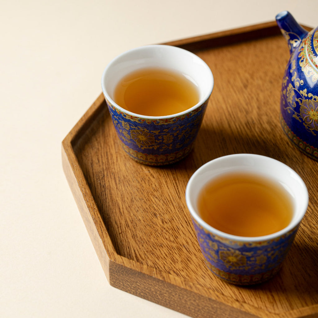 Two Qingding Gold Floral Tasting Cups filled with tea on a wooden tray