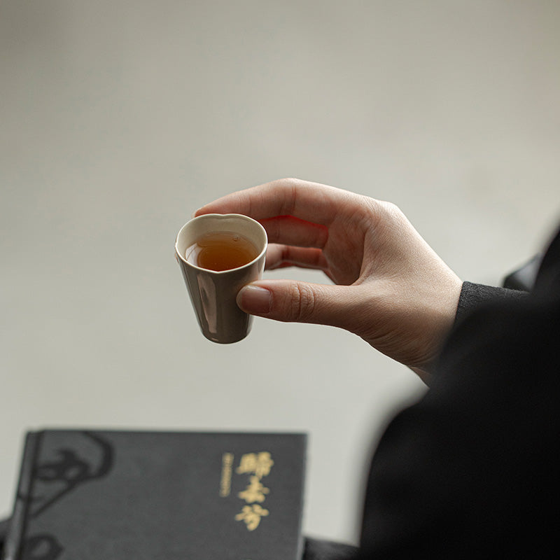 Wood Ash Zhixiao Tasting Cup held in hand
